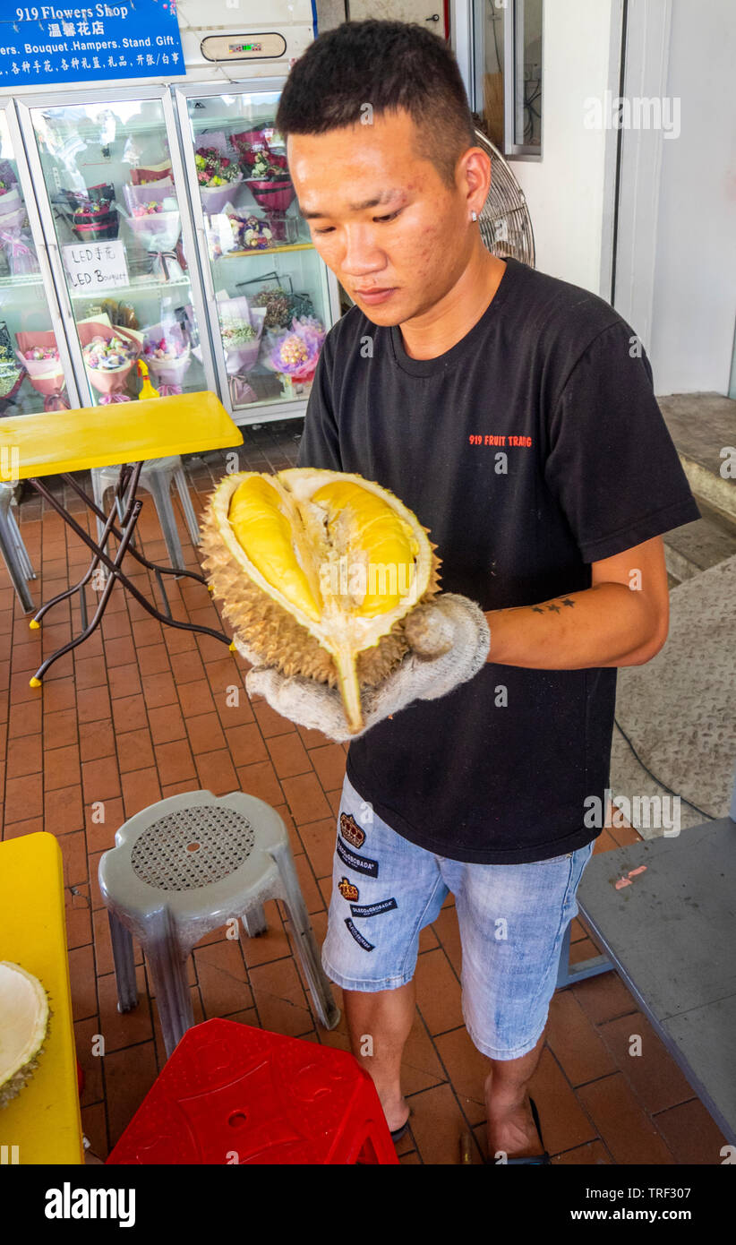 Male shopkeeper slicing and preparing tropical fruit durian for a customer Singapore. Stock Photo