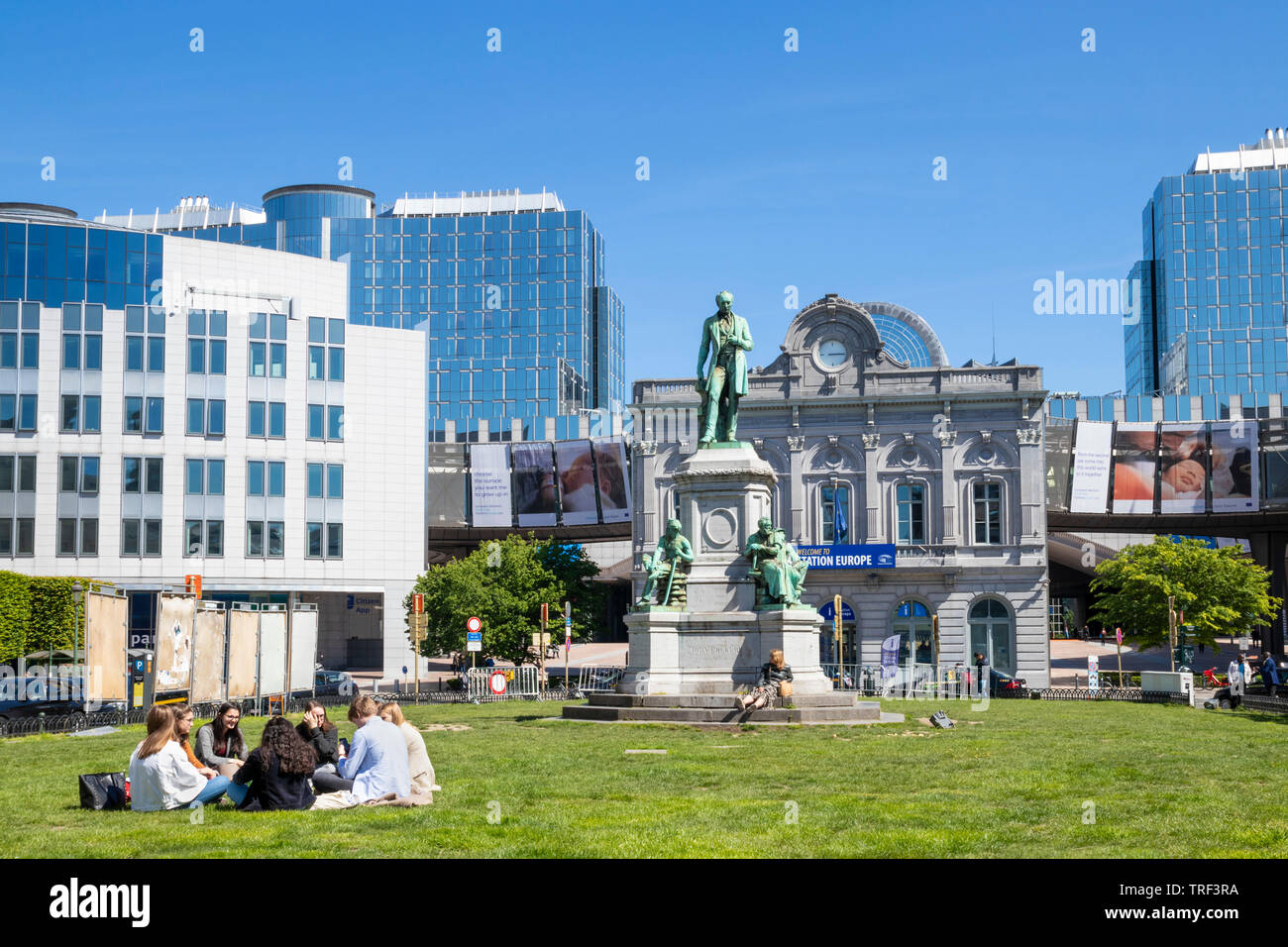 People on the grass in Place du Luxembourg PLUX Luxembourg Square Place du Luxembourg Ixelles statue of John Cockerill Brussels Belgium Eu Europe Stock Photo