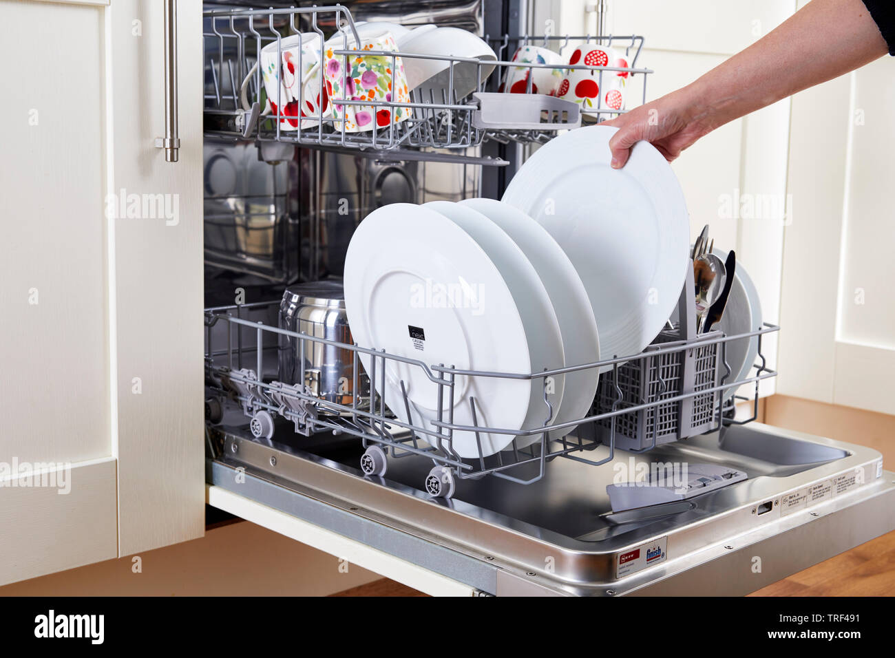 Woman unloading clean dishwasher Stock Photo