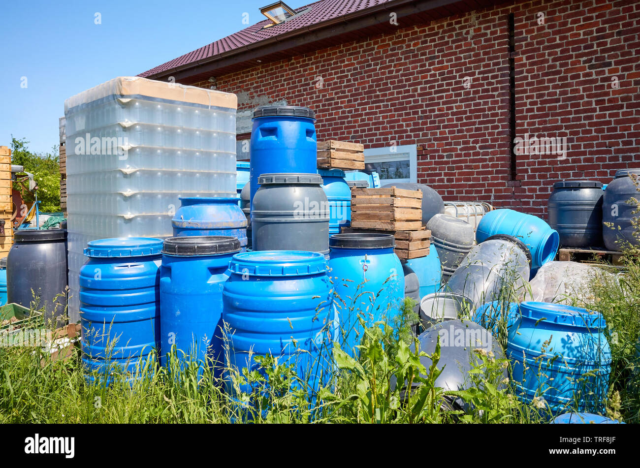 Empty plastic barrels and containers used in food processing piled at a farmyard. Stock Photo