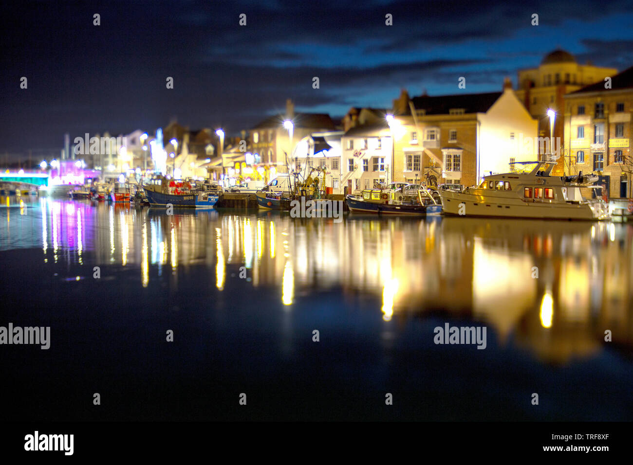 A  shot taken at night  with a lensbaby lens of boats moored alongside Weymouth Harbour in Dorset England Stock Photo