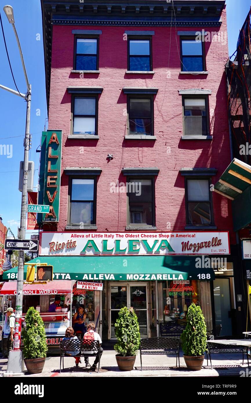 Couple sitting on bench in Little Italy Street outside Alleva Italian Dairy at Grand and Mulberry Streets, Manhattan, New York, NY Stock Photo