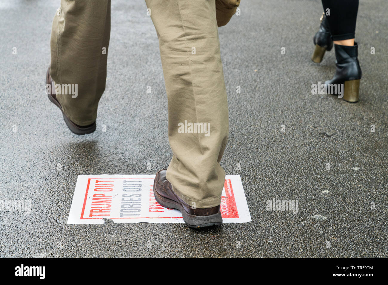 4th June 2019. London, UK. Anti Trump rally in Westminster. A man steps on the paper that says Trump Out Tories Out. Stock Photo