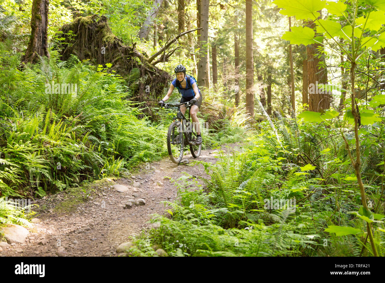 Happy, smiling woman having fun riding mountain bike biking on a trail. Women's outdoor adventure sports. Stock Photo