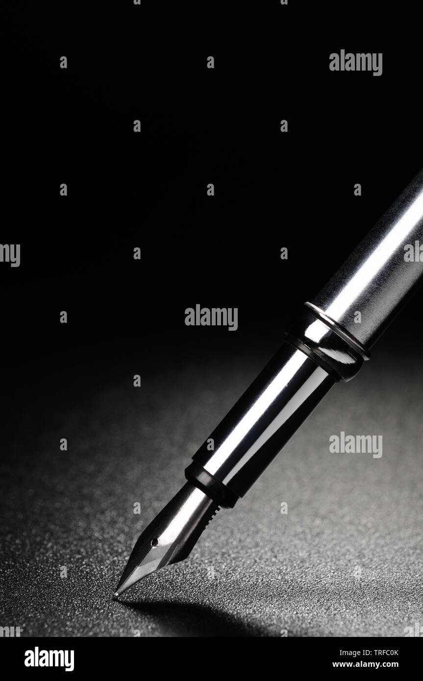 Old fountain pen on a black textured background Stock Photo