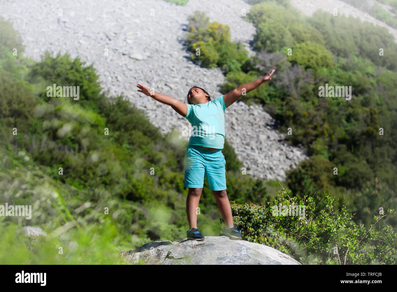 A pre teen girl celebrating her achievement of hiking a mountain and reaching the summit during summer camp athletic activity. Stock Photo