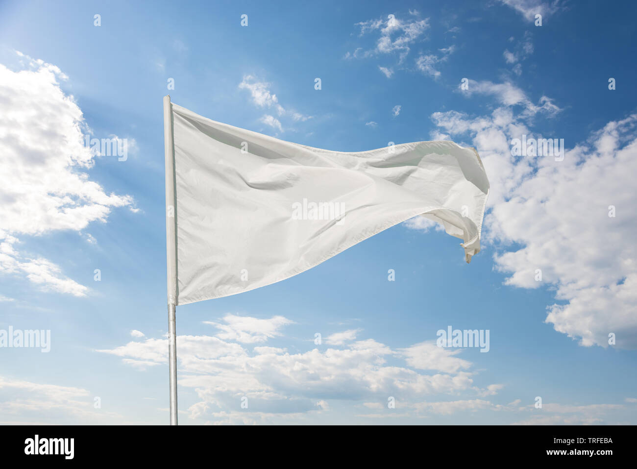 White flag against a blue sky with clouds fluttering in the wind Stock ...