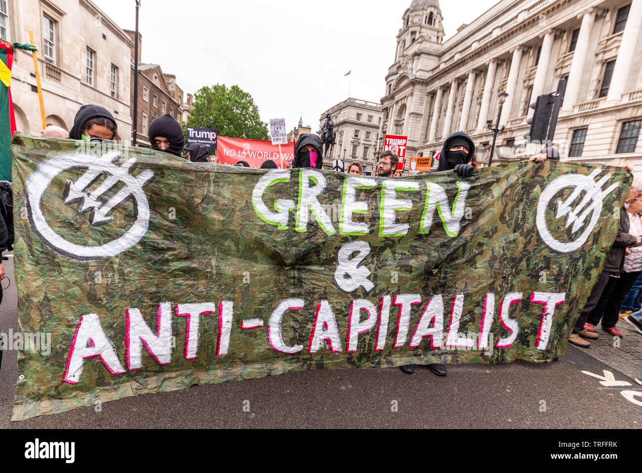 Green and anti-capitalist protest banner during demonstration in London, UK. Masked protesters Stock Photo