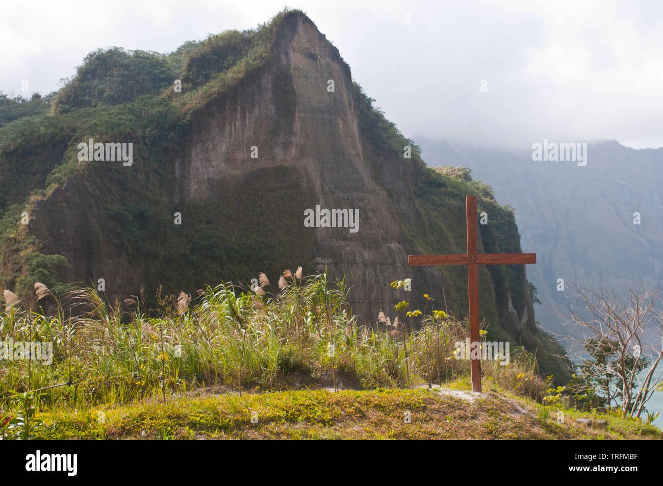 Upon reaching the peak of Mt. Pinatubo, one sees a view debt that overlooks the lake. A simple cross stands against the craters edges. Stock Photo