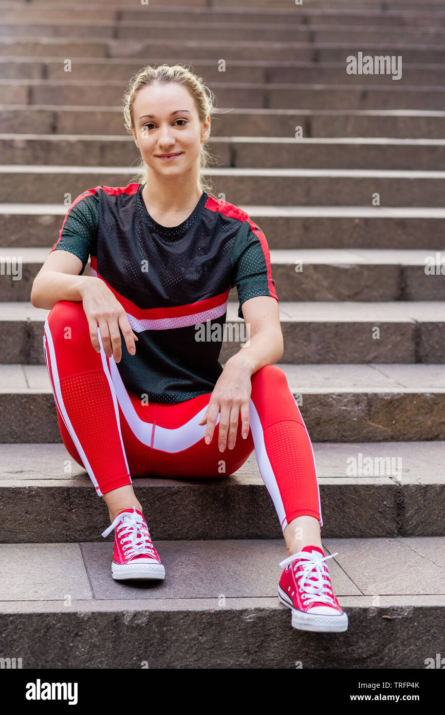 fit and active young woman in the city, doing stretches on some stairs Stock Photo