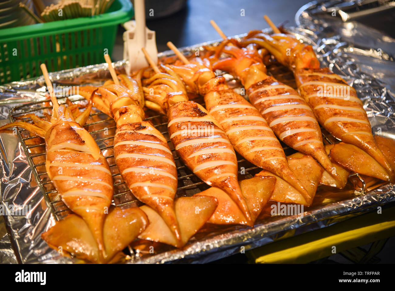 Grilled squid on grill with skewer sticks at street food Stock Photo - Alamy