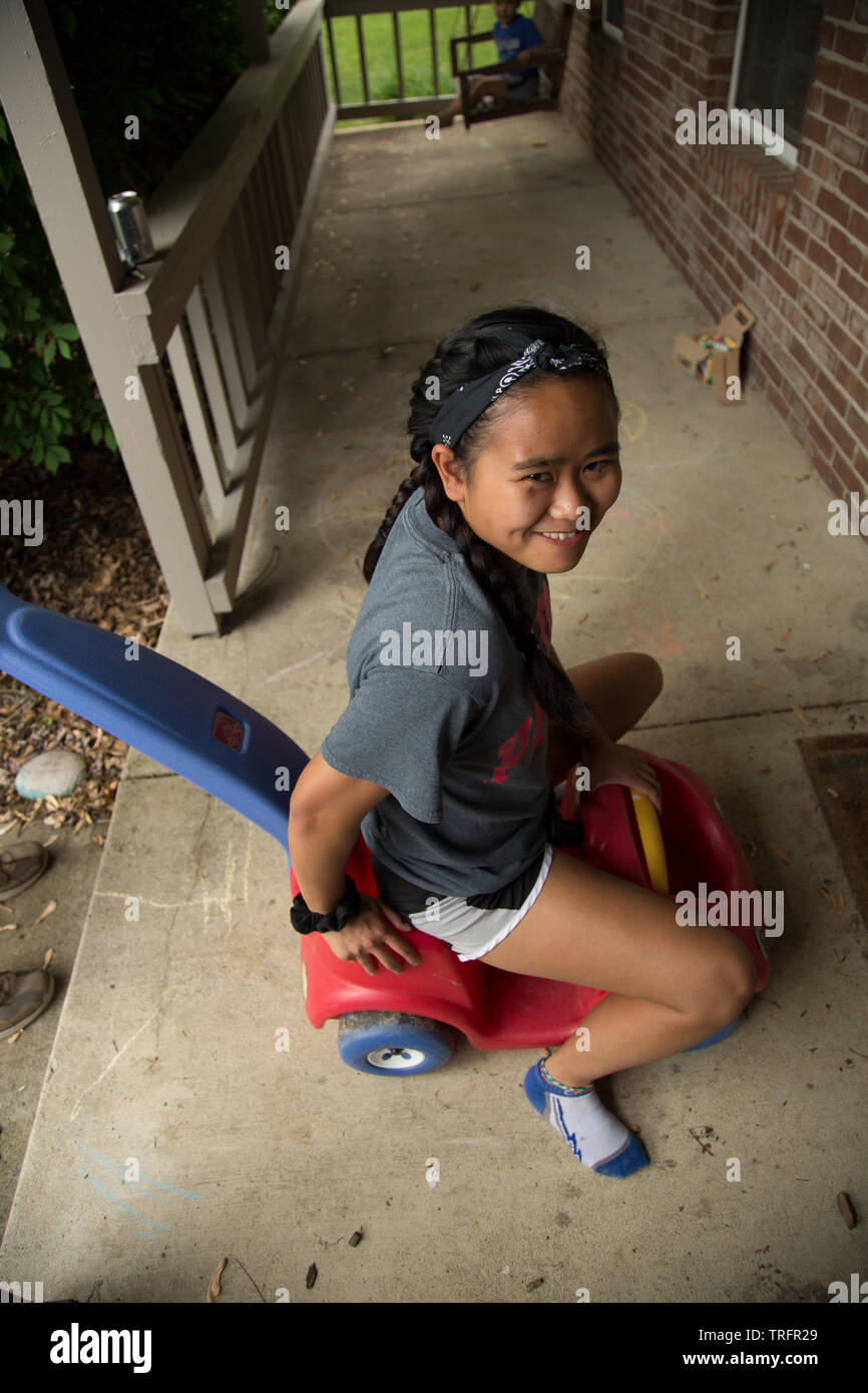 A pretty young teenage girl is too big for the toy she's riding. Stock Photo