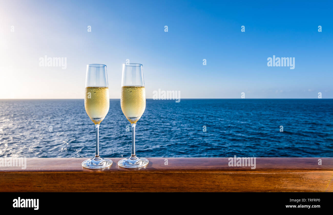 Two glasses of champagne on wooden railing of cruise ship. Sea
