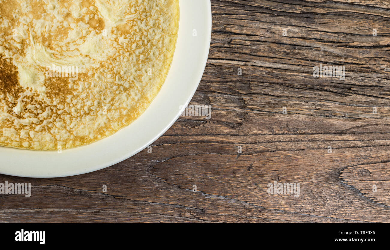 Pancake Day or Shrove Tuesday concept. French crepe on a plate. Rustic wooden background. Stock Photo
