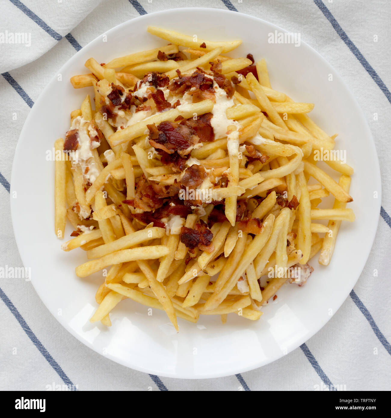 French fries with cheese sauce and bacon on a white plate, view from above.  Flat lay, overhead, top view Stock Photo - Alamy