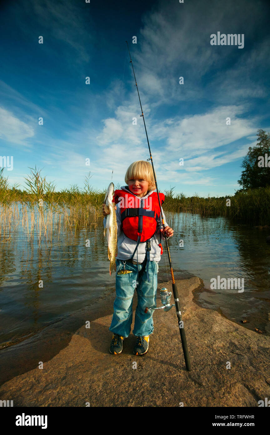 Young boy with his catch of Northern Pike, Esox lucius, in the lake Vansjø in Østfold, Norway. Vansjø is the largest lake in Østfold, and its surrounding lakes and rivers are a part of the water system called Morsavassdraget. September, 2006. Stock Photo