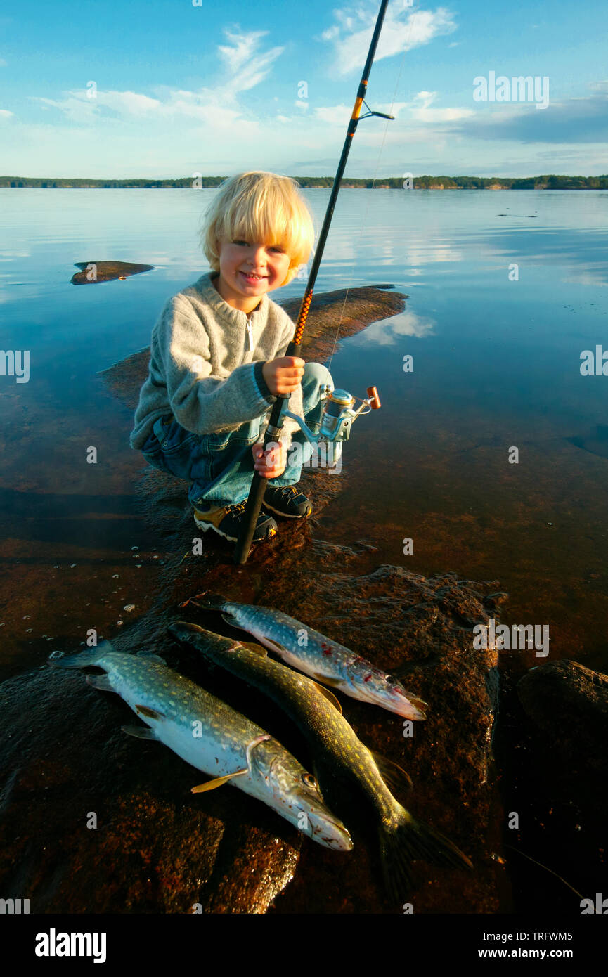 Young boy with his catch of Northern Pike, Esox lucius, in the lake Vansjø, Østfold, Norway. Vansjø is the largest lake in Østfold. September, 2006. Stock Photo