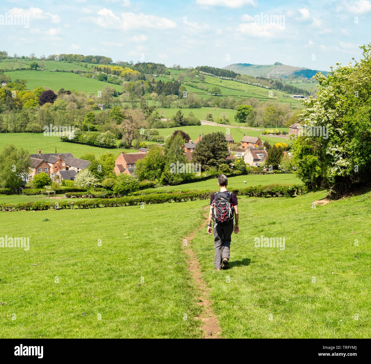 A female walker approaching the village of Mapleton in the Dove Valley of Derbyshire UK Stock Photo
