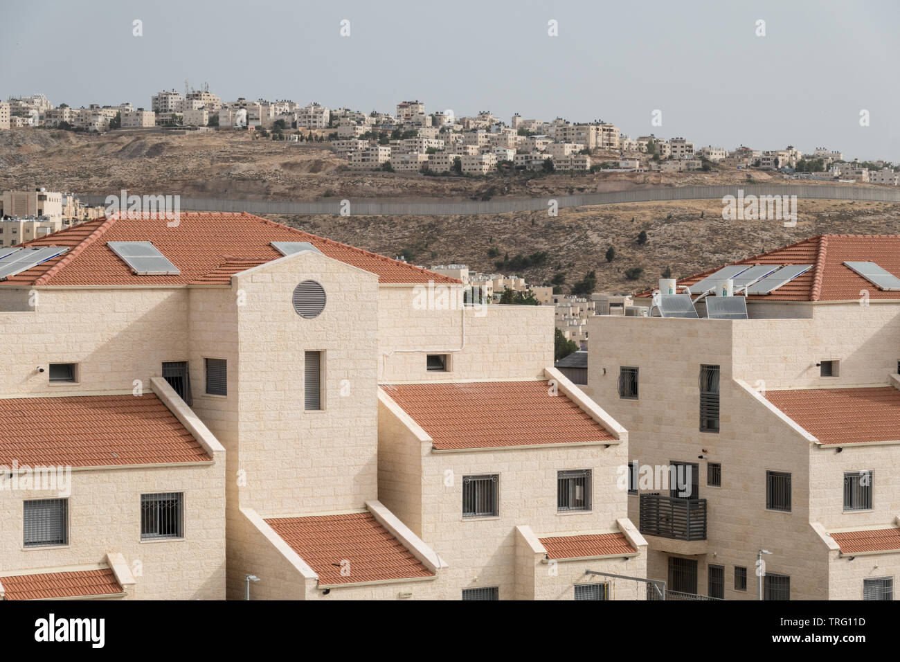 Jerusalem, Israel. 5th June, 2019. A northward view in Jerusalem's Pisgat Zeev neighborhood depicts recently constructed red roofed homes in the foreground with Israel's security barrier in mid ground and the outskirts of Palestinian Qalandiya and Jaba beyond. Israel's Housing Ministry recently published tenders for the construction of 805 new housing units in the Ramot and Pisgat Zeev neighborhoods drawing EU condemnation (1st June, 2019) stating “The European Union is strongly opposed to Israel's settlement policy, including in East Jerusalem, which is illegal under international law and an Stock Photo