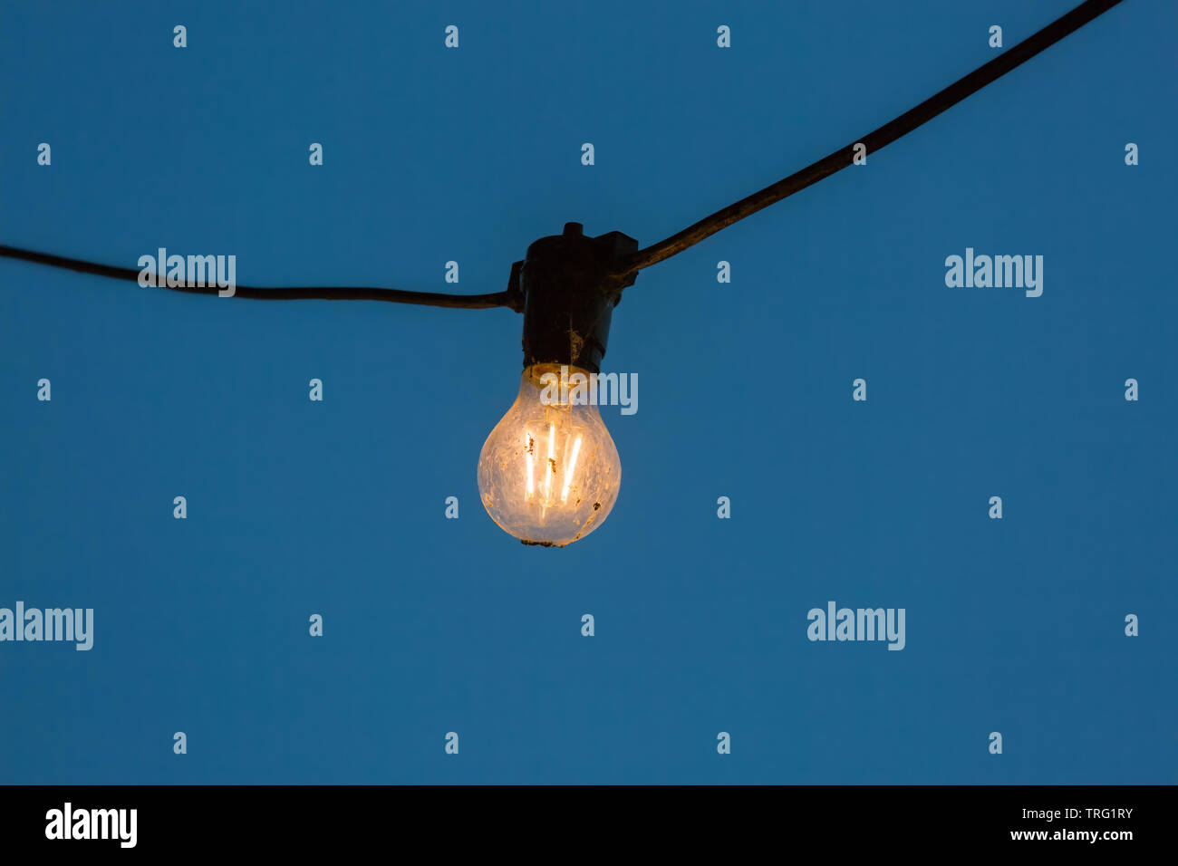 Light Bulb Illuminated in Front of a Clear Blue Sky Stock Photo