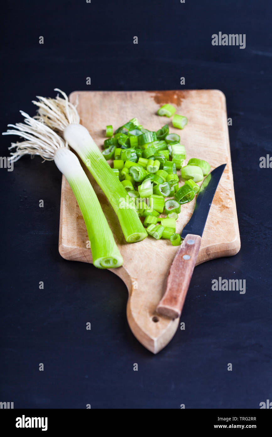 Fresh green organic chopped onions and knife on a cutting board. Raw ...