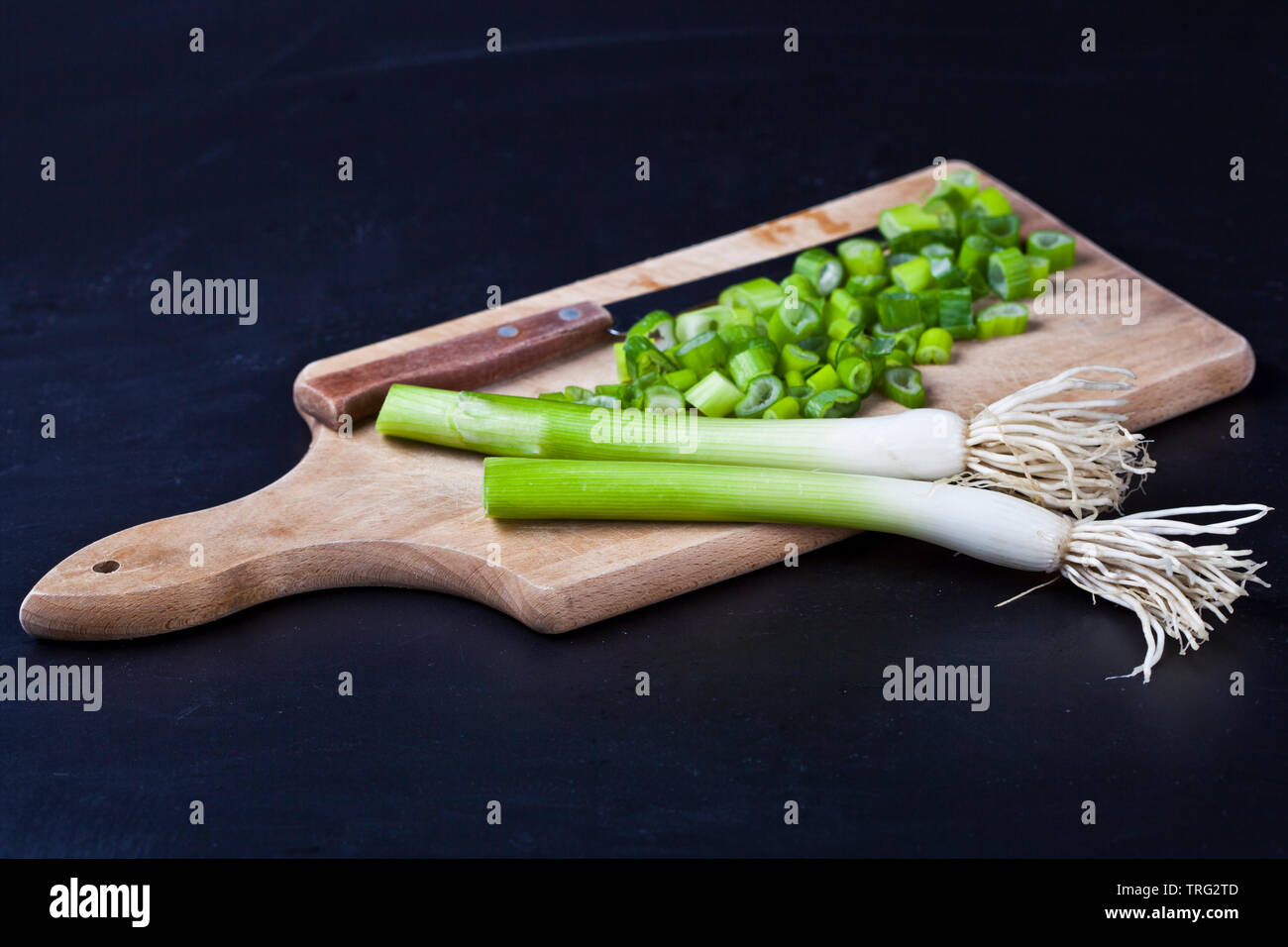 Fresh green organic chopped onions and knife on a cutting board. Raw ...