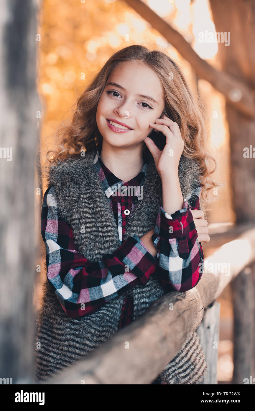 Smiling teen blonde girl 12-14 year old wearing casual clothes outdoors. Looking at camera. Teenager hood. Stock Photo