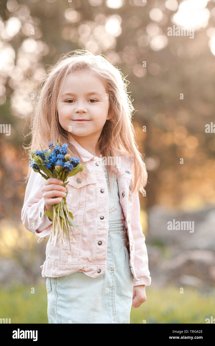 Smiling kid girl 4 5 year old holding fresh flowers wearing casual clothes outdoors. Looking at camera. Childhood Stock Photo Alamy