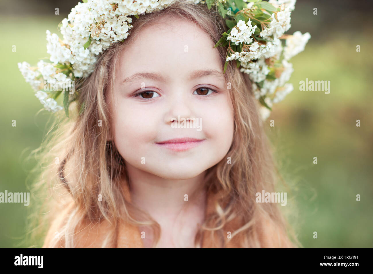 Cute kid girl 4-5 year old with flowers in hairstyle outdoors. Looking at  camera. Childhood Stock Photo - Alamy
