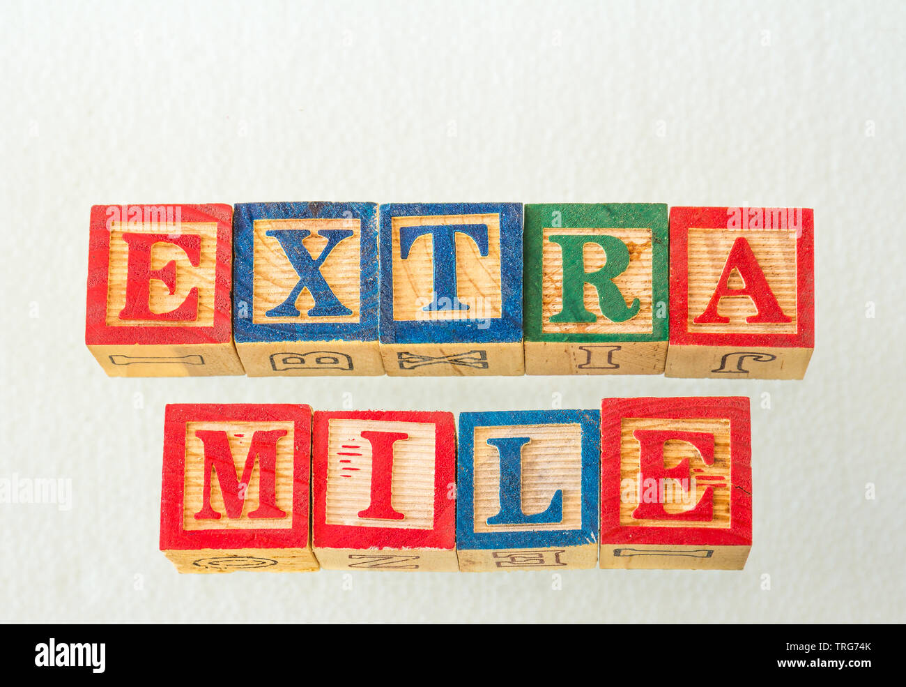 The term extra mile visually displayed using colorful wooden blocks on