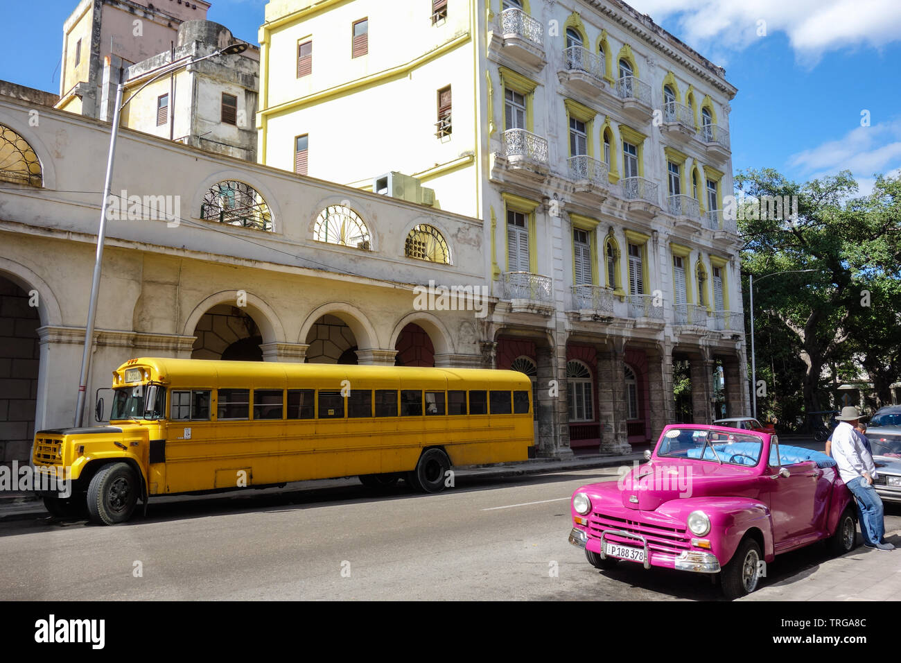 Havana, Cuba - 30th January 2018: Classic, old yellow schoolbus and a pink cabriolet parking in the streets of Havana Stock Photo