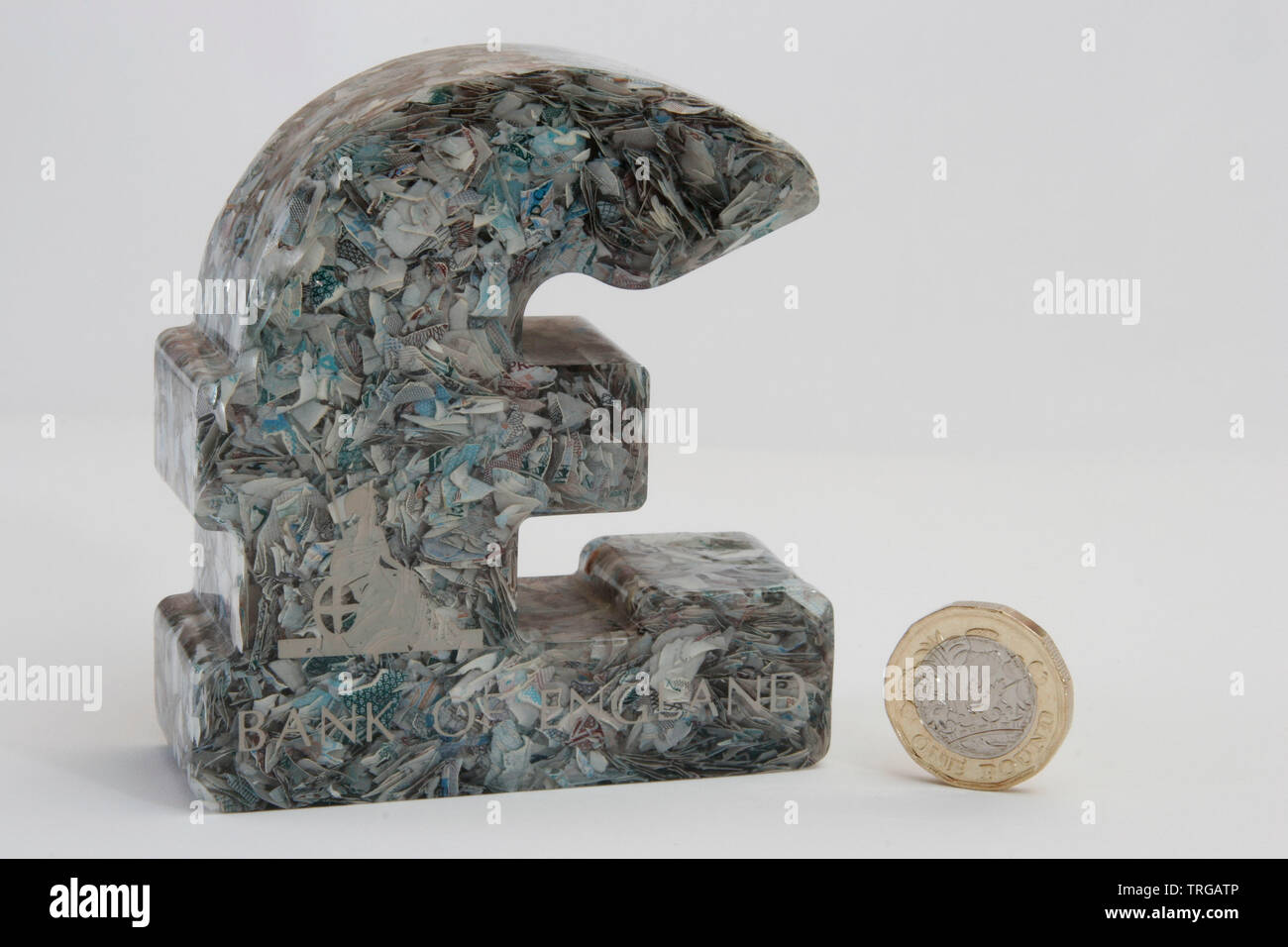 British Pound paper weight made from chopped up £5 notes next to £1 coin UK Stock Photo