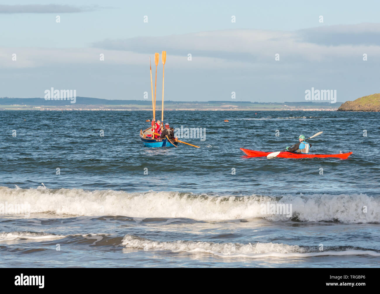 Loony Dook, New Year's Day: West Bay, Firth of Forth, North Berwick, East Lothian, Scotland, UK. with rowing skiff and canoeist in the sea Stock Photo