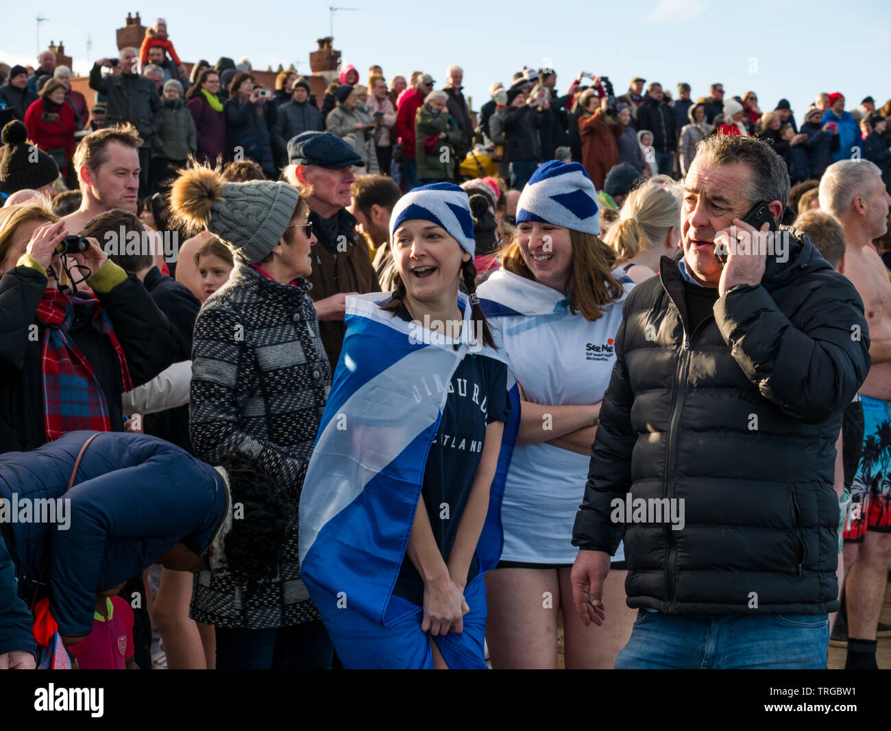 Loony Dook, New Year's Day: People brave cold water, West Bay, Firth of Forth, North Berwick, East Lothian, Scotland, UK. Young women in saltire hats Stock Photo