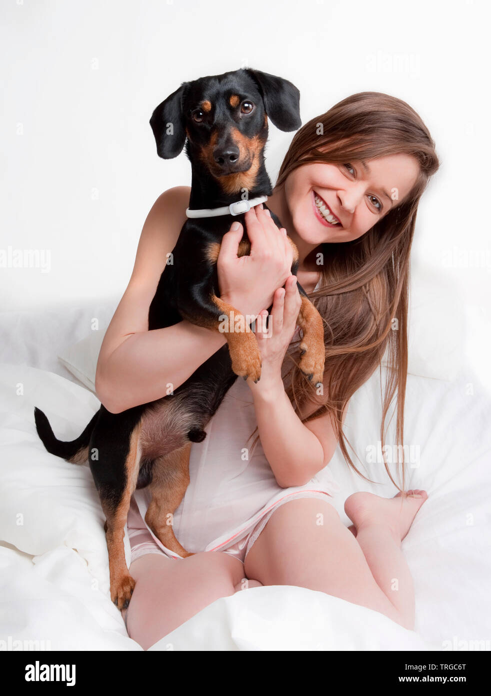 Woman in bed holding her dog. Stock Photo