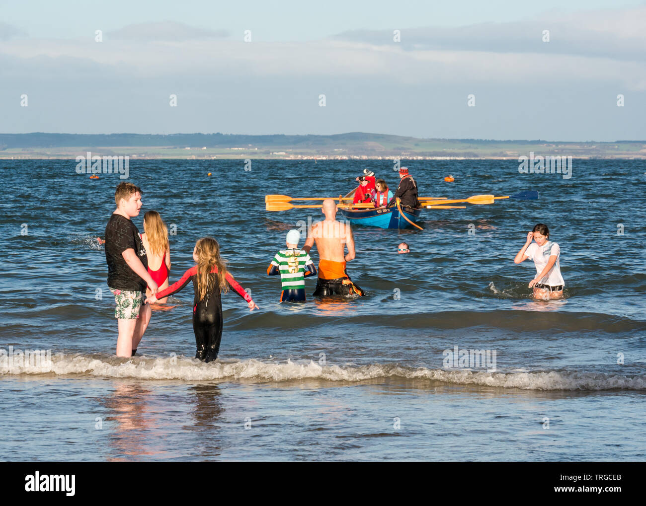 Loony Dook, New Year's Day: People brave cold water of West Bay, Firth of Forth, North Berwick, East Lothian, Scotland, UK,. People in sea with rowing Stock Photo