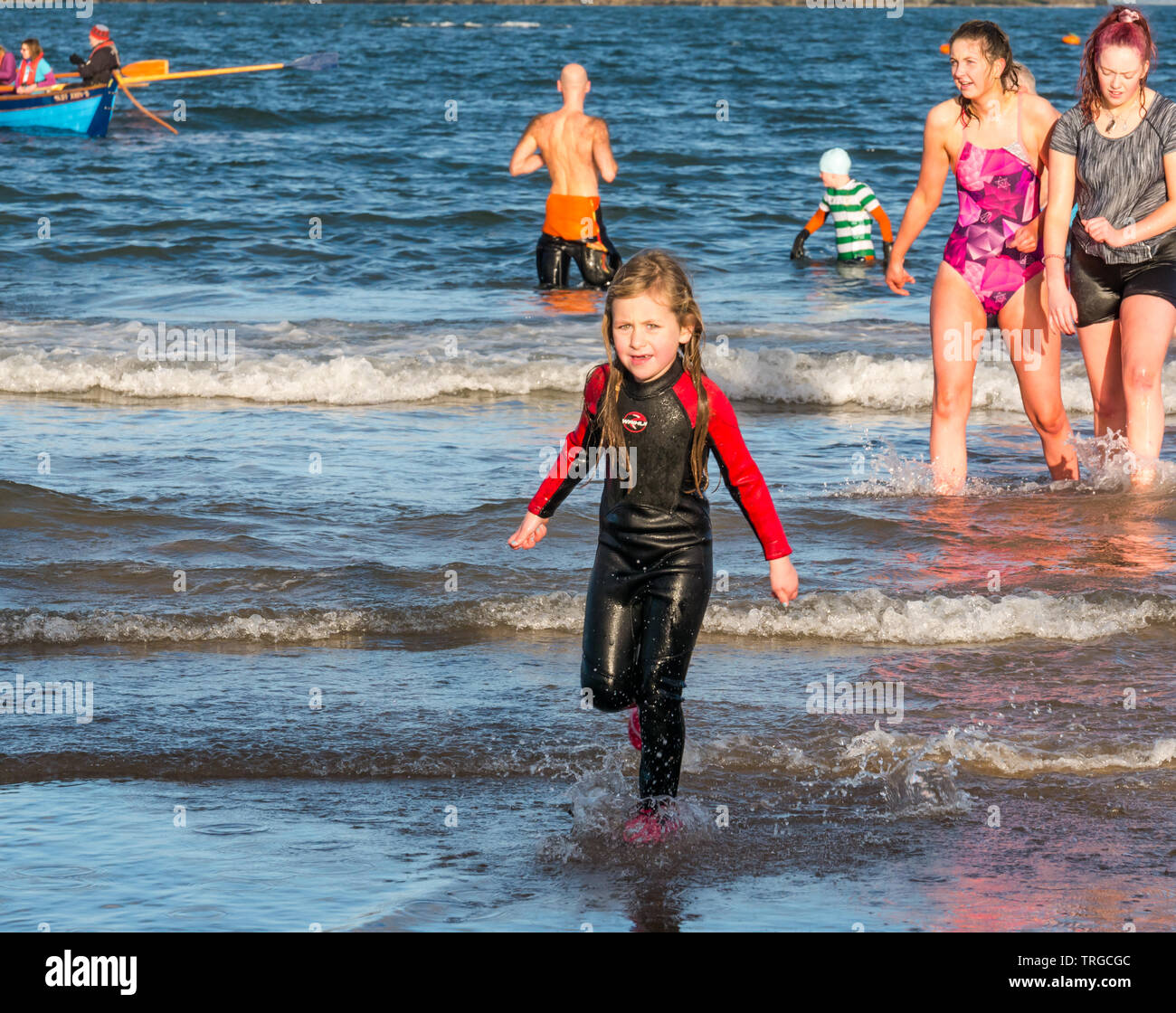 Loony Dook, New Year's Day: People brave cold water of West Bay, Firth of Forth, North Berwick, East Lothian, Scotland, UK. Young girl in wetsuit Stock Photo