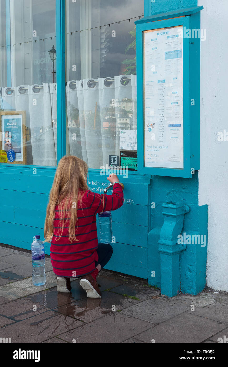 Child drawing tap water in Dartmouth Quay Stock Photo