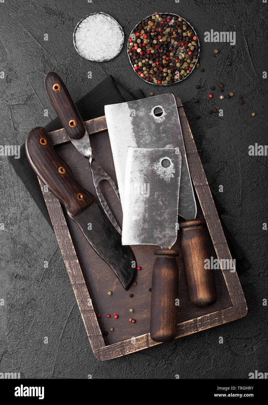 Vintage meat knife and fork and hatchet in old wooden box on black