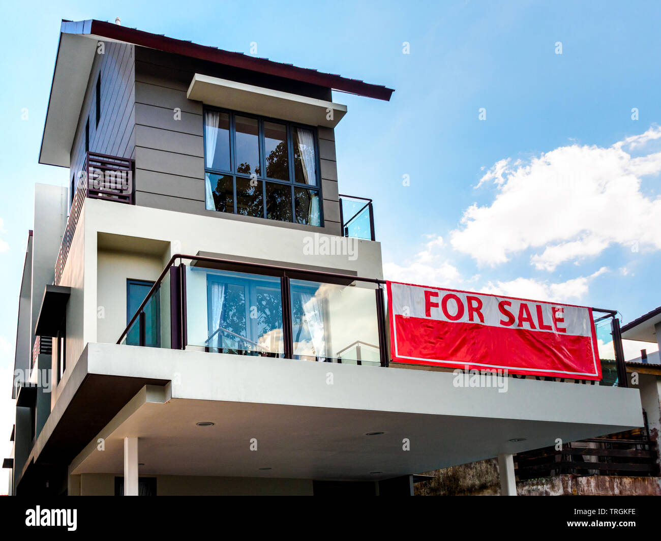 SINGAPORE, 15 MARCH 2019 - Low angle off-centre view of a house with red 'for sale' sign. Stock Photo