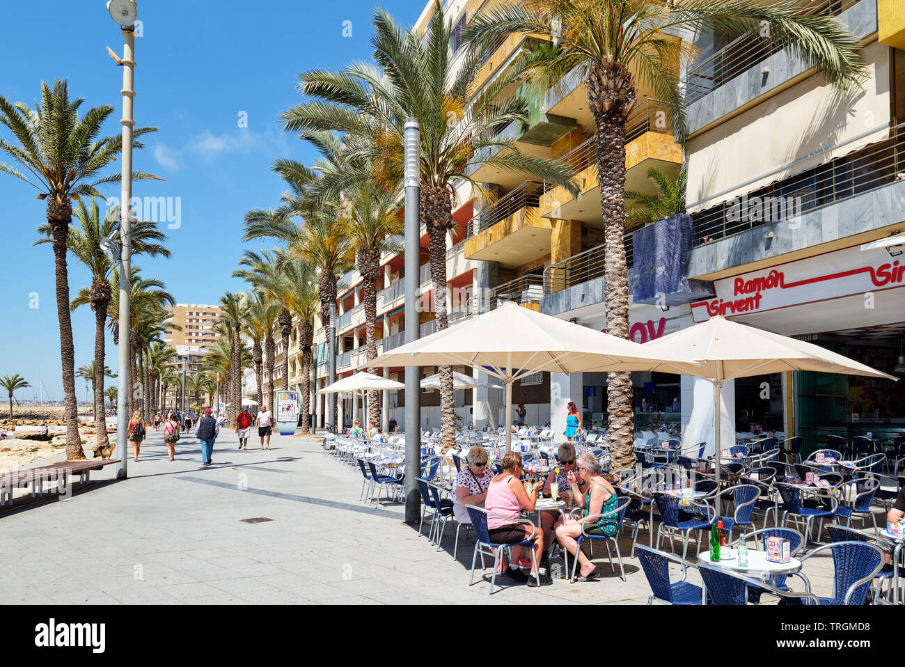 Torrevieja, Spain - May 16, 2019: People sitting in side walk cafe in the seafront promenade of Torrevieja resort city, vacationers enjoy weather Stock Photo