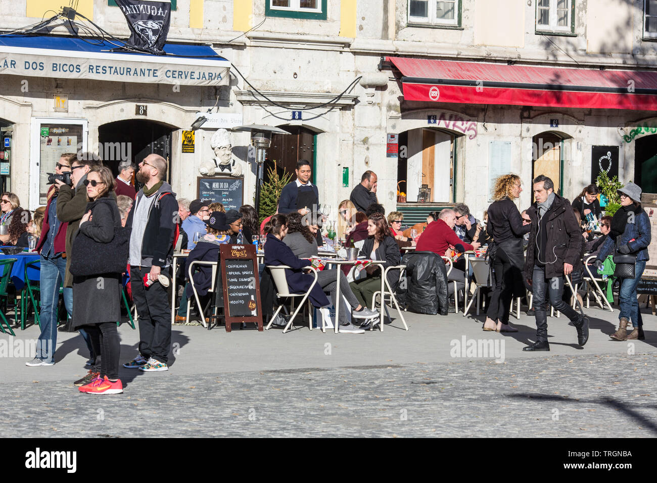 Lisbon/Portugal - February 10, 2018: People sitting and resting in street cafe of Alfama, old district of Lisbon. Stock Photo