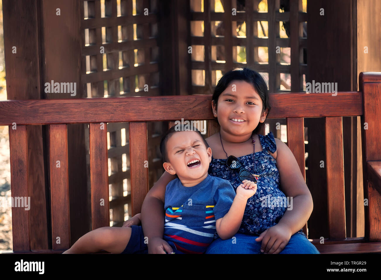 Big sister with arm around her little brother who is excited and yelling out loud. Stock Photo