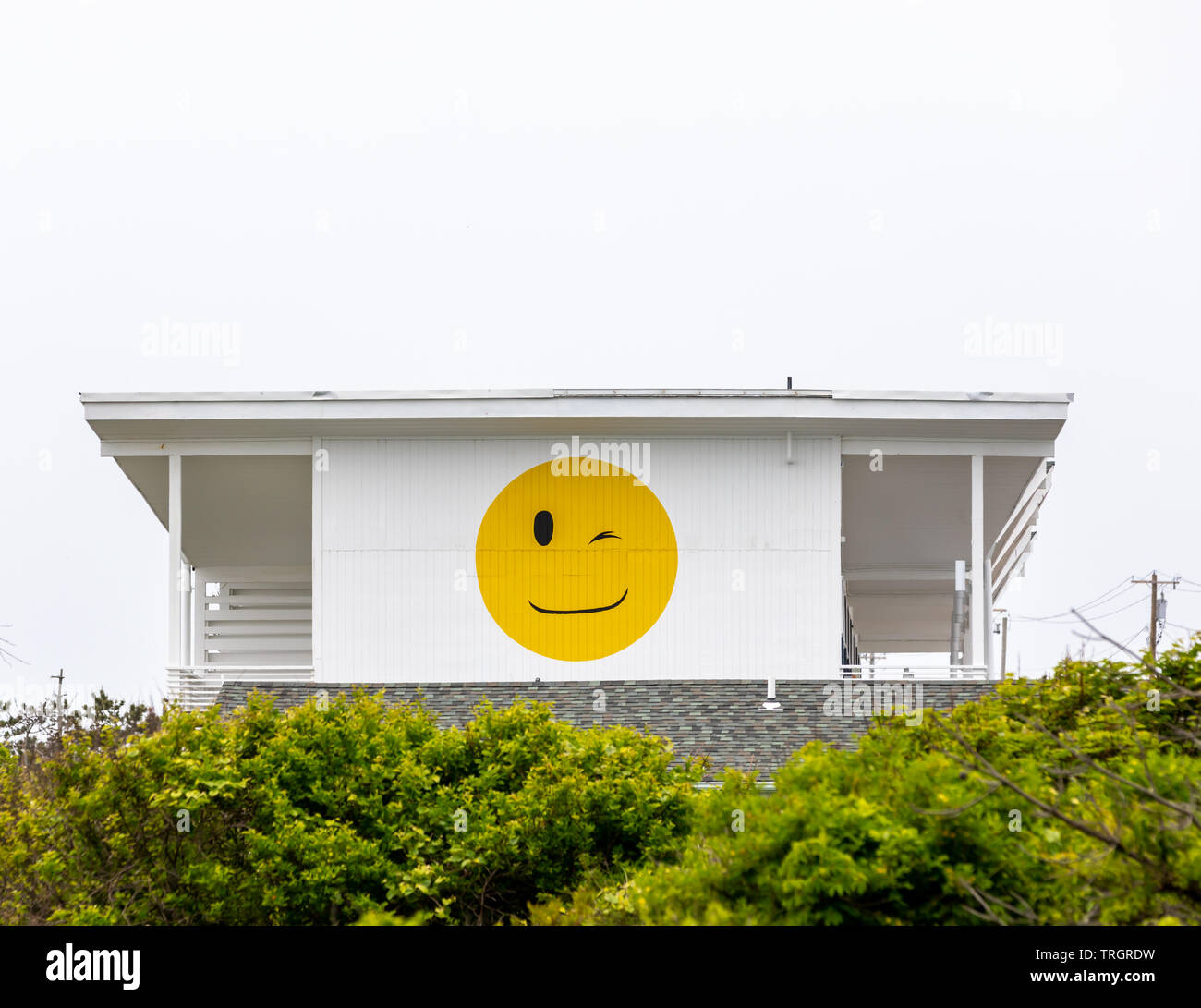 Large yellow smiley face with a winking eye on the side of a Montauk Hotel, NY Stock Photo