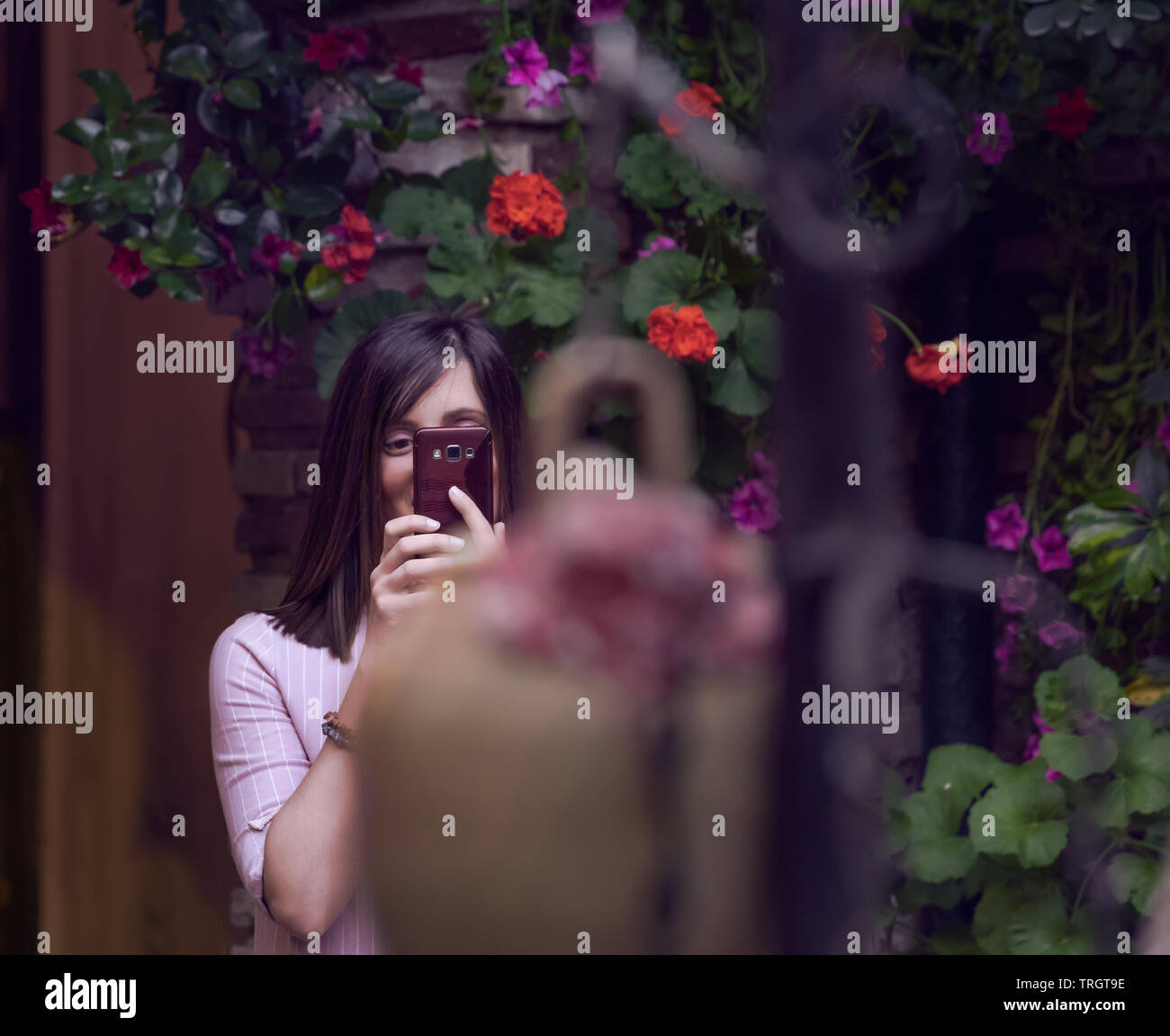 Cordoba, Spain - May 16, 2019: A young woman taking a photo with her mobile in a flowery environment Stock Photo