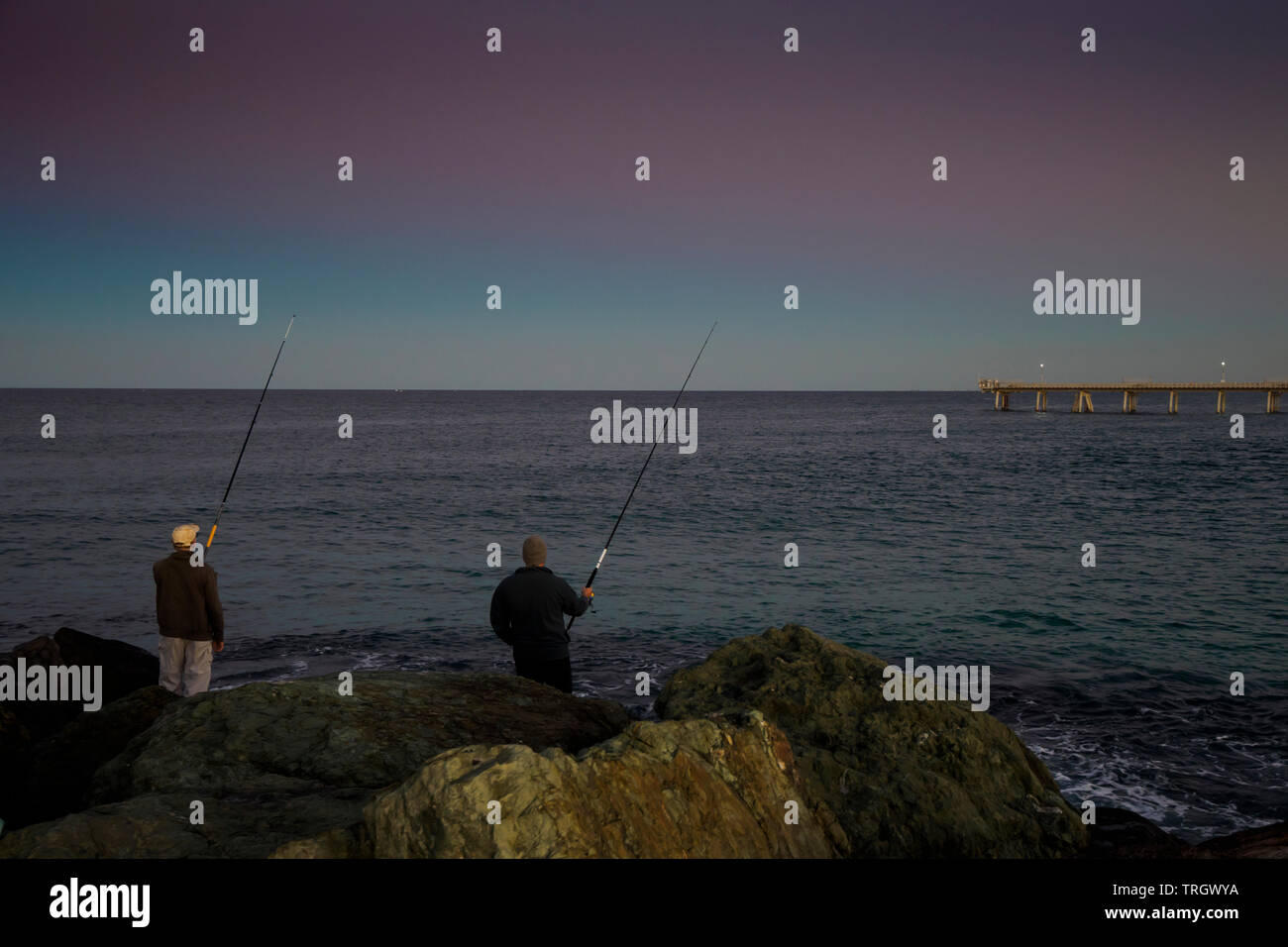 fishermen fishing from rocks at sunset gold coast, queensland australia Stock Photo