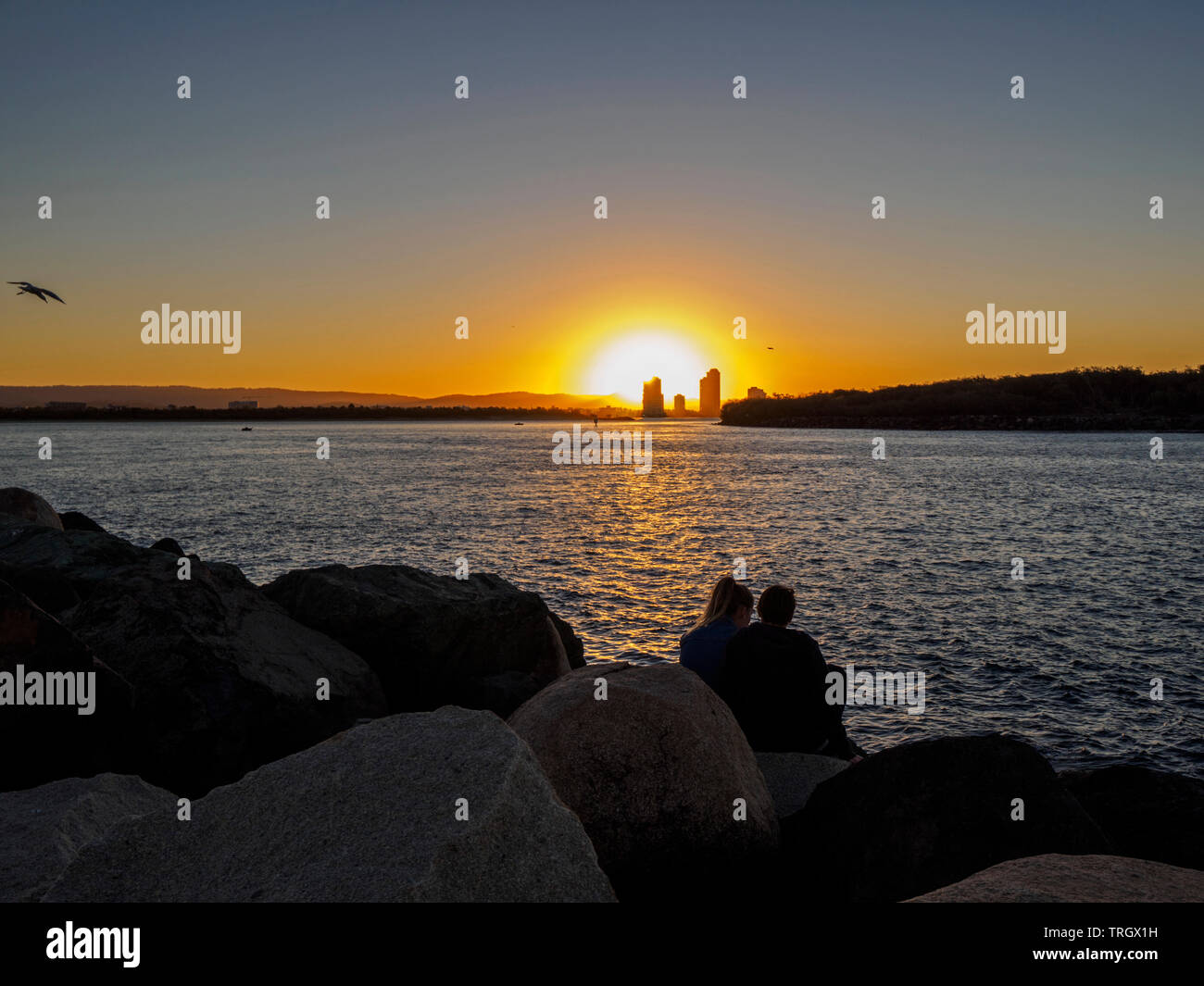 Couple cuddling watching dramatic sunset gold coast, queensland australia Stock Photo