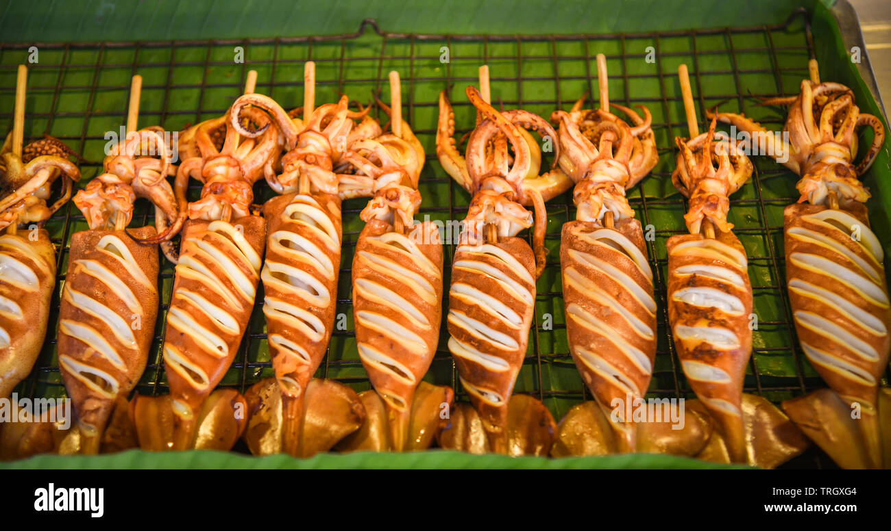 Grilled squid on grill with skewer sticks at street food Stock Photo