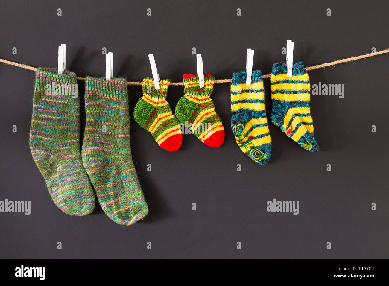 Several pairs of colorful woolen socks of various sizes hanging on a ...