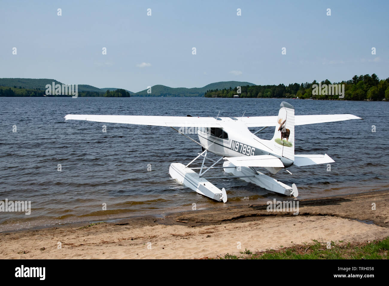 A Cessna 180J airplane with pontoons parked on the beach on Lake Pleasant at the village park in Speculator, NY USA Stock Photo